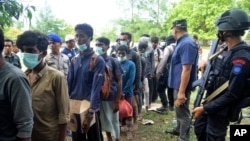 Security officers stand by Rohingya refugees after they arrived on Indra Patra beach in Ladong village, Aceh province, Indonesia, Dec. 25, 2022.