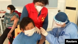 A medical worker administers a dose of a vaccine against COVID-19 to an elderly resident, during a government-organized visit to a vaccination center in Zhongmin village on the outskirts of Shanghai, Dec. 21, 2022.