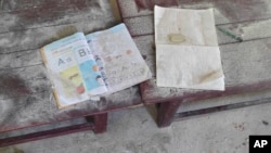 An alphabet book and a notebook lie on top of an elevated wooden floorboard of a middle school in Let Yet Kone village in Tabayin township in the Sagaing region of Myanmar on Sept. 17, 2022, the day after an air strike hit the school.