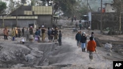 People inspect their ash-covered village following the eruption of Mount Semeru in Lumajang, East Java, Indonesia, Monday, Dec. 5, 2022.