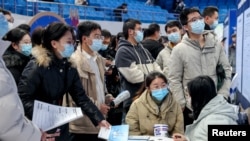Job seekers approach the booth of an employer at a job fair in Wuhan, Hubei province, China Feb. 9, 2023.