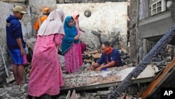 People inspect the ruins of their house in a neighborhood affected by a fuel depot fire in Jakarta, Indonesia, March 4, 2023.
