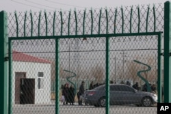 FILE - Residents line up inside the Artux City Vocational Skills Education Training Service Center, which was revealed by leaked documents to be a forced indoctrination camp at the Kunshan Industrial Park in Artux in western China's Xinjiang region,Dec. 3, 2018.