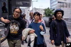 Elizabeth Tang, center, the former chief executive of the now-disbanded pro-democracy group Hong Kong Confederation of Trade Unions (HKCTU), walks out of the police station along with former Chairperson Joe Wong, left, and former vice-chairperson Leo Tang, right, March 11, 2023.
