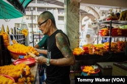 A worker at the Erawan Shrine in Bangkok cools down by standing by an electric fan and eating ice-pops in Bangkok, Thailand, April 23, 2023.