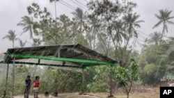 Children stand under a roadside shelter to protect from rain before Cyclone Mocha hits in Sittwe, Rakhine State, May 14, 2023.