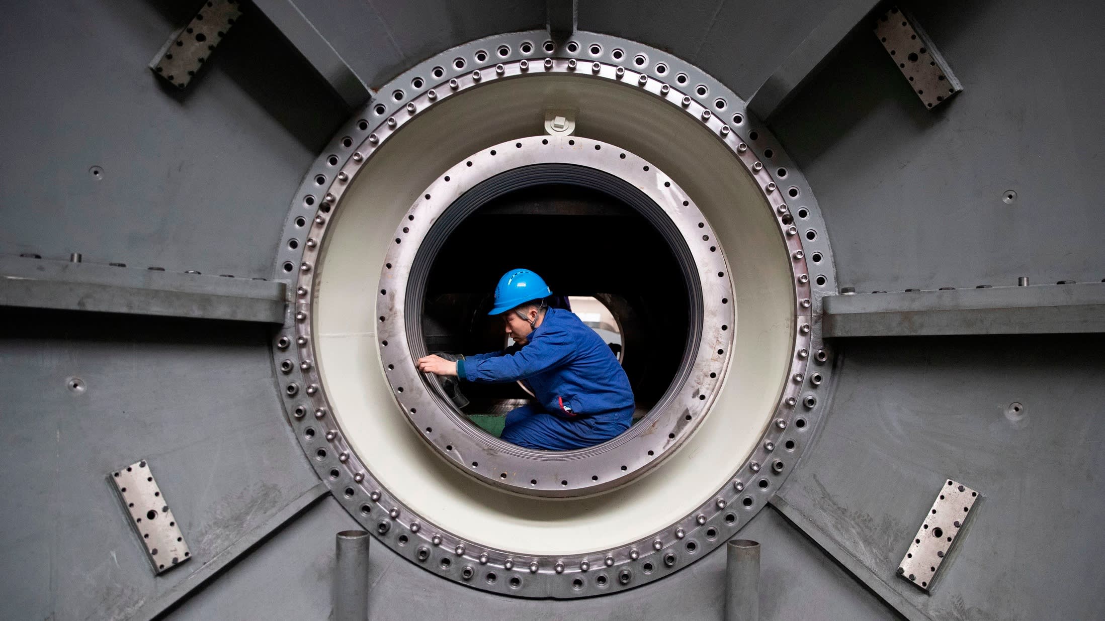 A worker measures the size of equipment at the Harbin Turbine Company in northeastern China