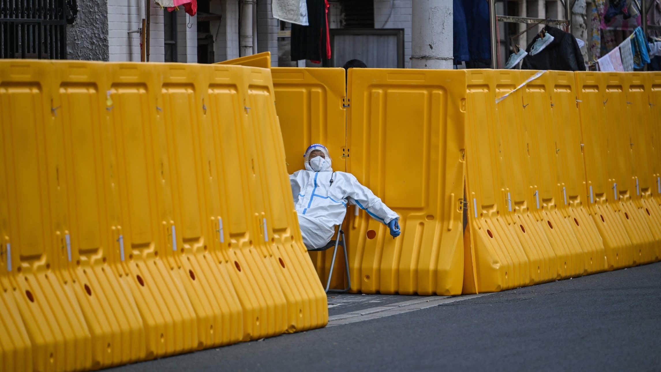 A pandemic worker guards the entrance of a locked down neighbourhood in Shanghai in March 2022