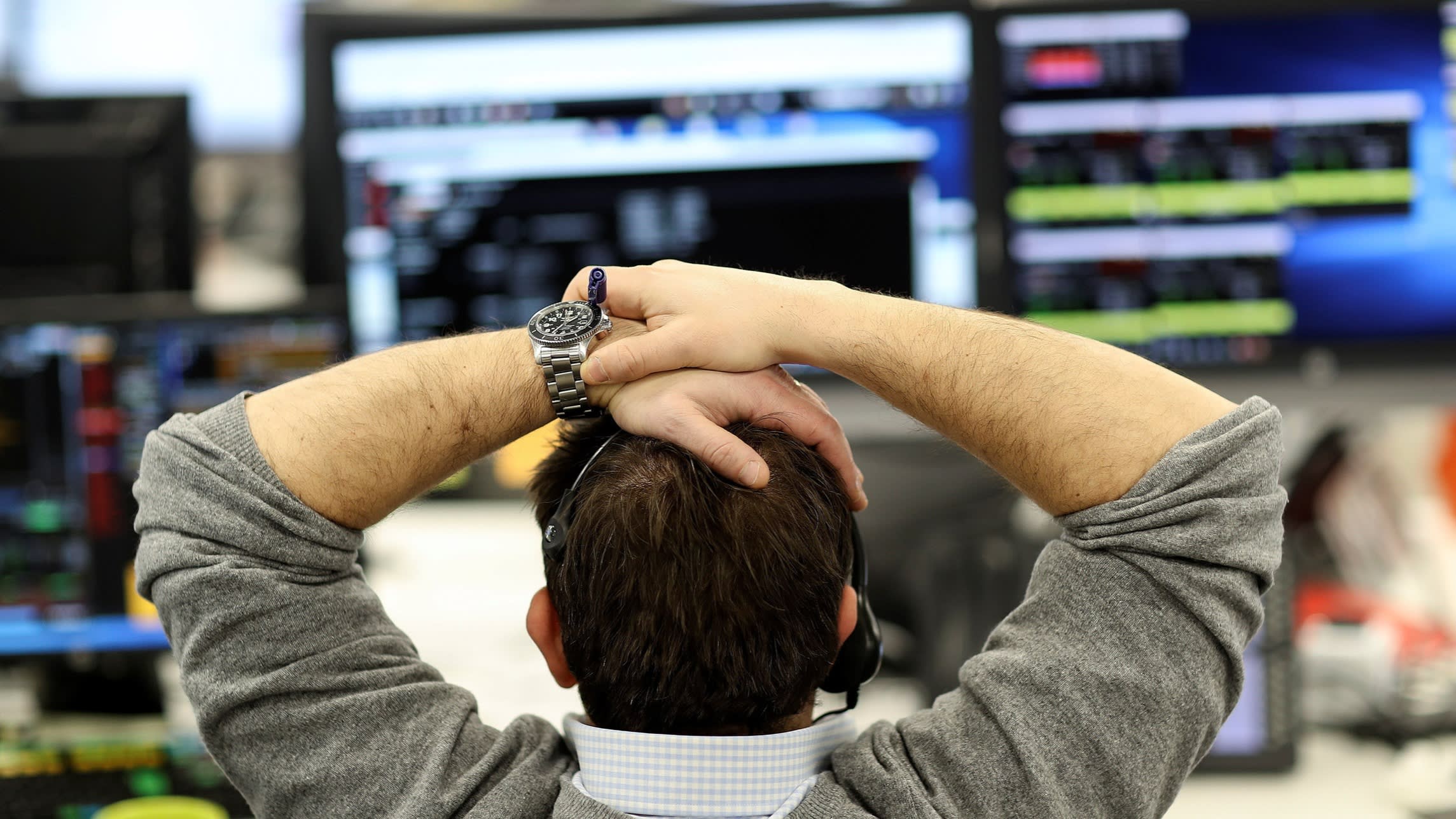 A broker looks at financial information on computer screens on a trading floor