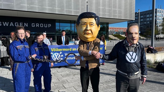 Human rights activists portraying Chinese President Xi Jinping, Volkswagen CEO Oliver Blume, and two chained and handcuffed Uyghur laborers stage an outdoor protest during Volkswagen's annual shareholder meeting in Berlin, Germany, May 10, 2023. Credit: World Uyghur Congress