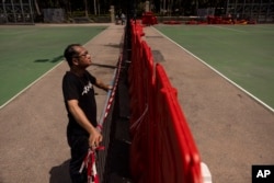 Richard Tsoi, former leader of now-disbanded Hong Kong Alliance in Support of Patriotic Democratic Movements of China, poses for photographs next to a closed pitch at Victoria Park in Hong Kong, Monday, May 29, 2023.