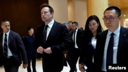 Tesla Chief Executive Officer Elon Musk, center, walks next to Tesla's Senior Vice President Tom Zhu and Vice President Grace Tao as he leaves a hotel in Beijing, May 31, 2023.