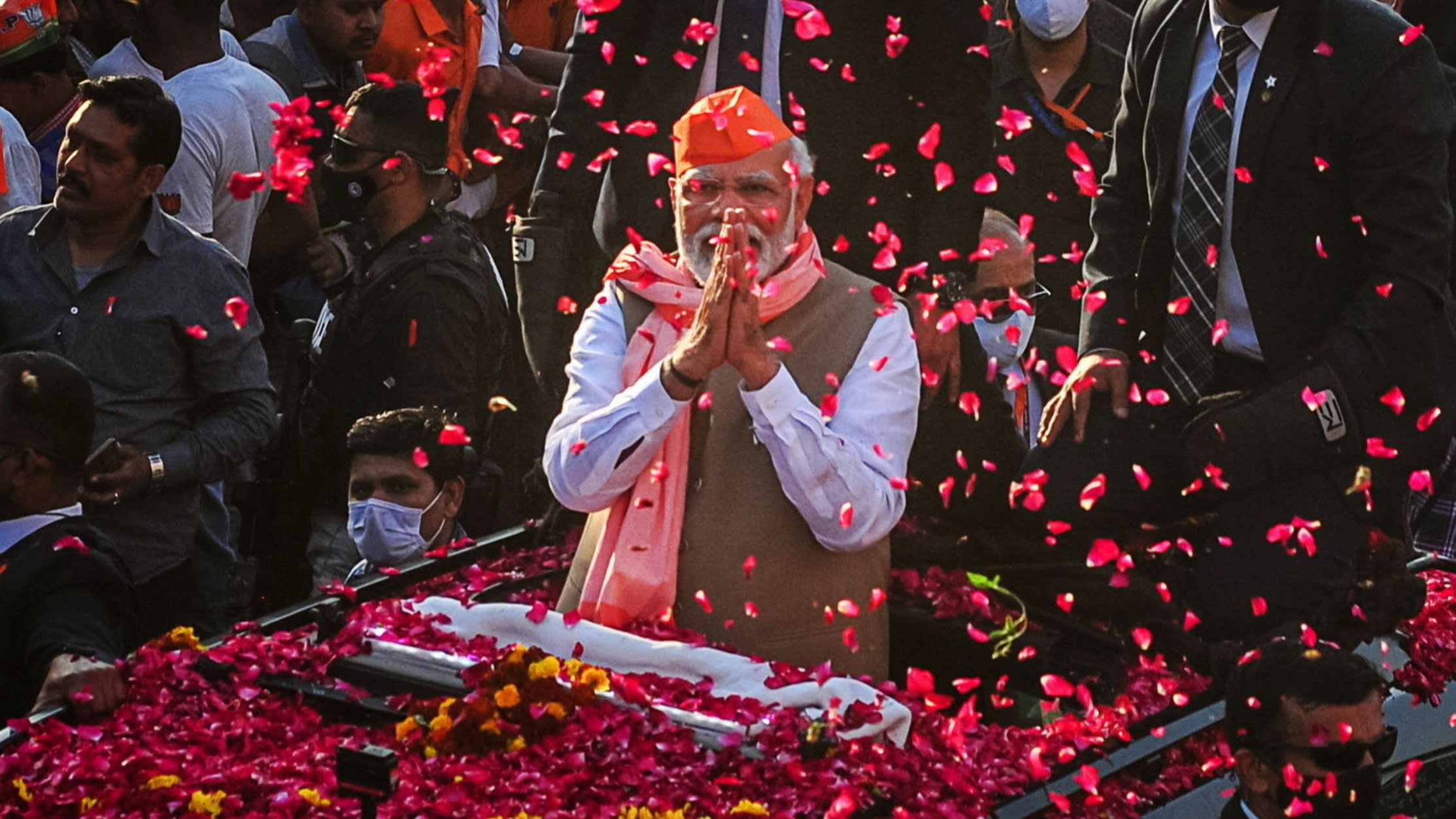Narendra Modi greets crowds of supporters as they shower him in rose petals