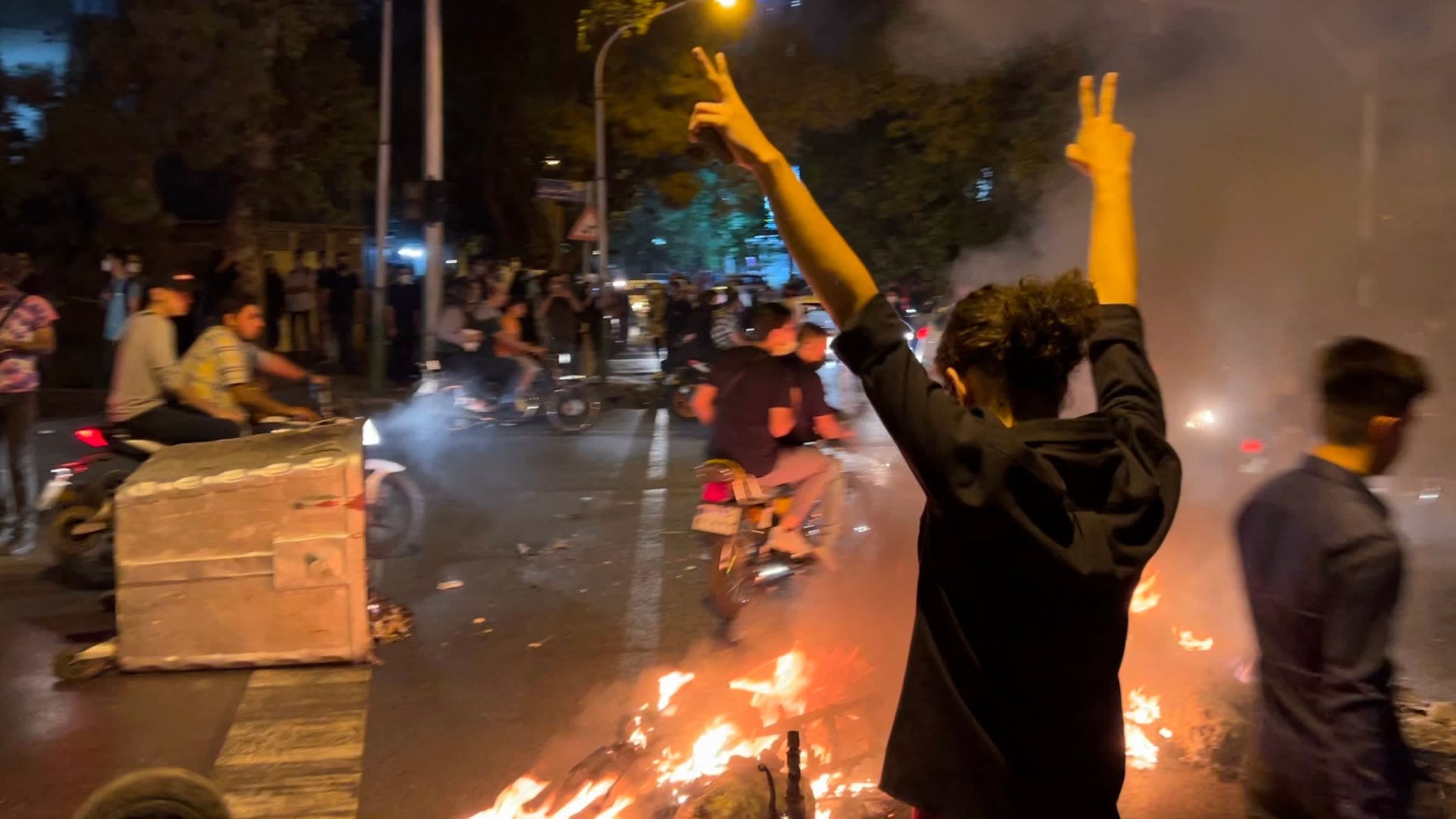 A protester raises his arms on a street in Tehran