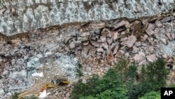 In this photo released by Xinhua News Agency, rescuers search for people missing in a landslide triggered by torrential rains at a highway construction site in central China's Hubei province, July 9, 2023.