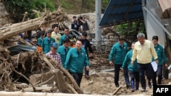 South Korea's President Yoon Suk Yeol (C) walks past piles of fallen trees at a village, where more than a third of houses were damaged in landslides and two people remain missing, in Yecheon on July 17, 2023.