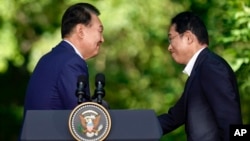 South Korea's President Yoon Suk Yeol, left, shakes hands with Japan's Prime Minister Fumio Kishida after a news conference with President Joe Biden, Aug. 18, 2023, at Camp David near Thurmont, Md.