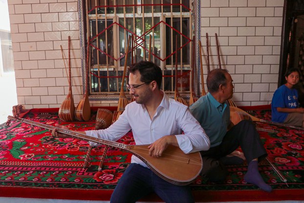 ENG_UYG_AmbassadorsVisit_08112023.1.jpg Hector Dorbecker, counselor for economic-commercial and financial affairs at the Embassy of Mexico in Beijing, tries to play dutar, a long-necked two-stringed lute, in Jiayi village of Xinhe county, northwest China's Xinjiang Uygur Autonomous Region, Aug. 2, 2023. Credit: Zhao Chenjie/Xinhua via Getty Images