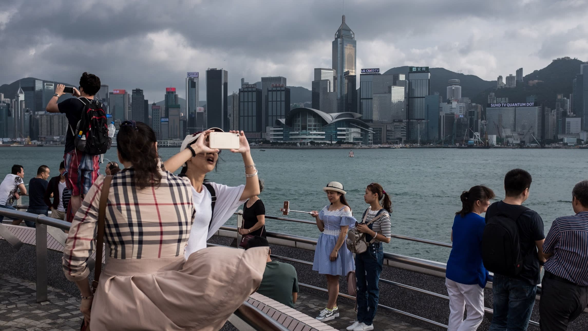 Mainland Chinese tourists take selfies on a viewing deck overlooking Victoria harbour in Hong Kong