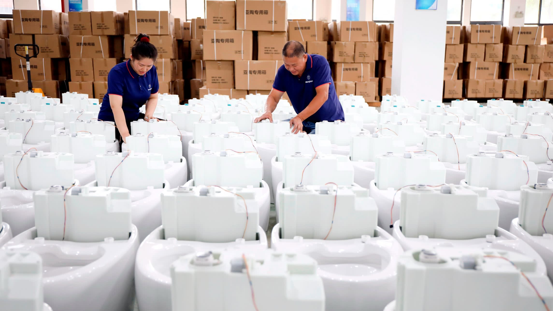 Employees work on an assembly line of smart toilets