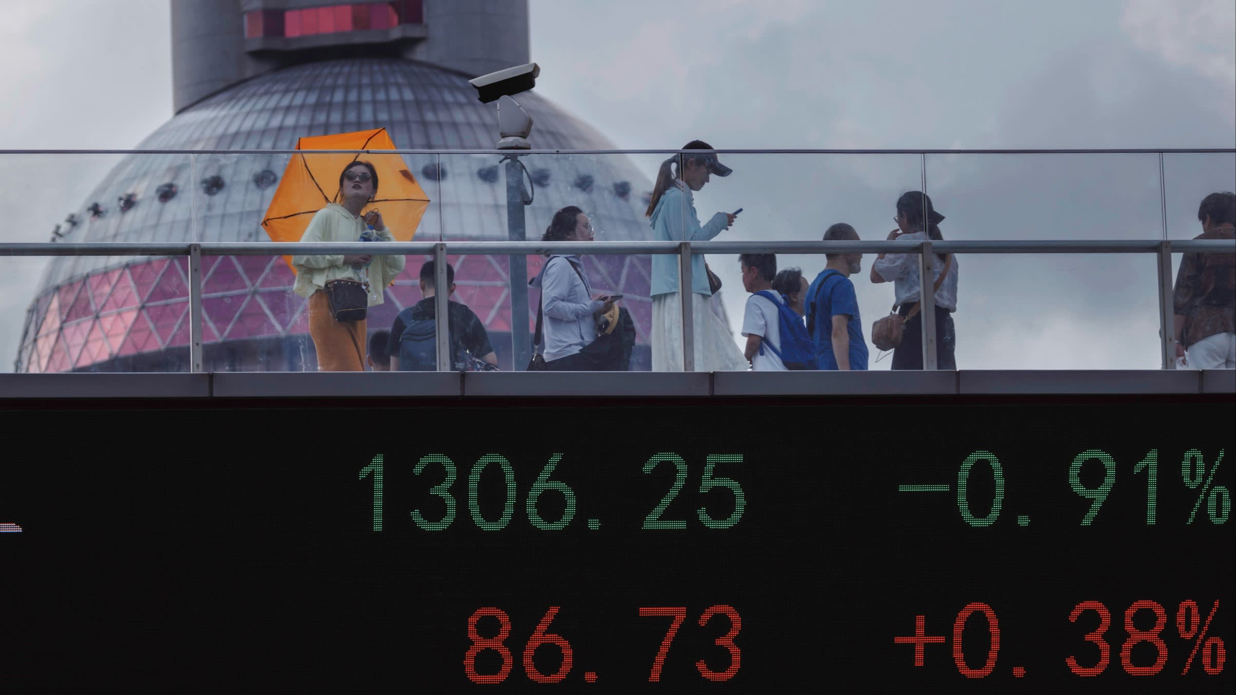 A pedestrian bridge with a screen showing stock exchange data in Shanghai