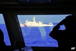 FILE - In this photo provided by the Philippine Coast Guard, a Chinese Coast Guard ship sails near a Philippine Coast Guard vessel during its patrol at Bajo de Masinloc, March 2, 2022.