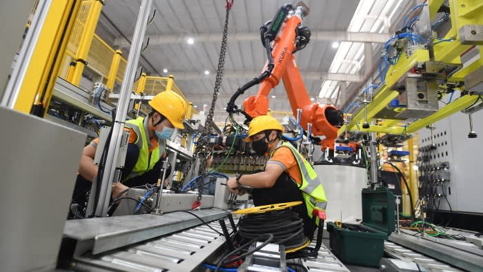 Workers adjust robots at a manufacturer of smart equipment in Wuhan, China
