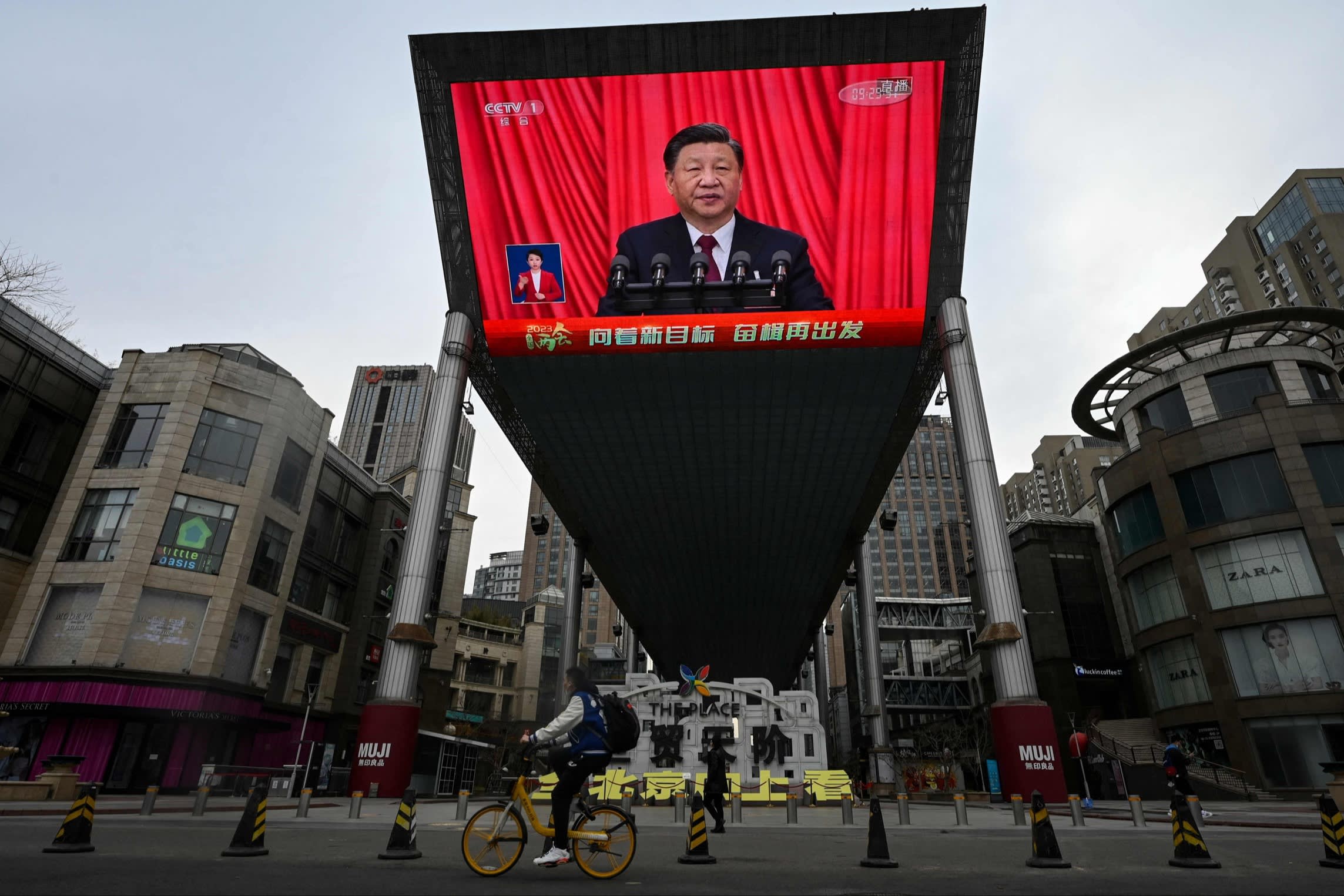 An outdoor screen shows live coverage of Xi Jinping’s speech during the closing session of the National People’s Congress at the Great Hall of the People in Beijing