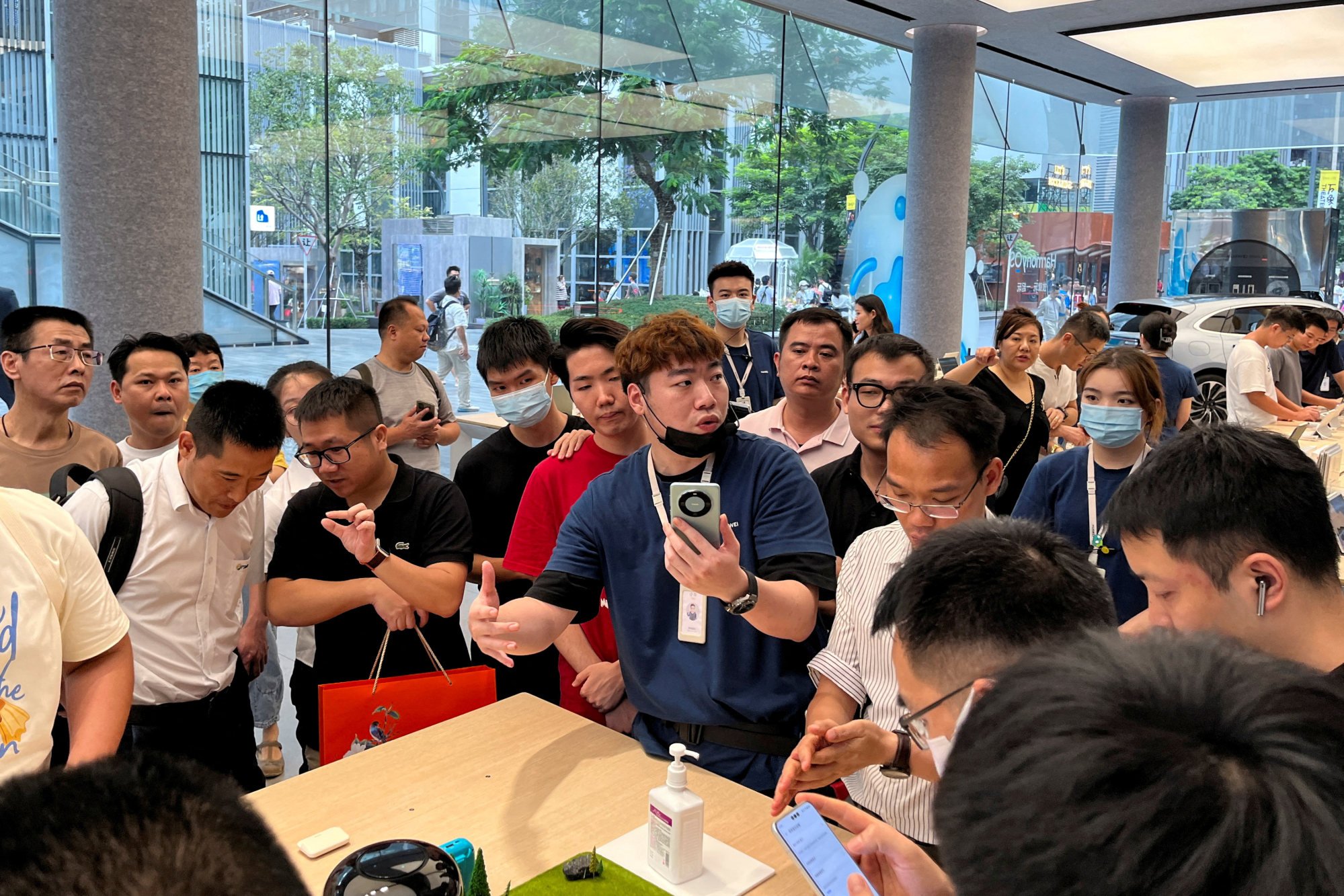 A staff member introduces the new Huawei Mate 60 smartphone to customers at the brand’s flagship store in Shenzhen. Photo: Reuters