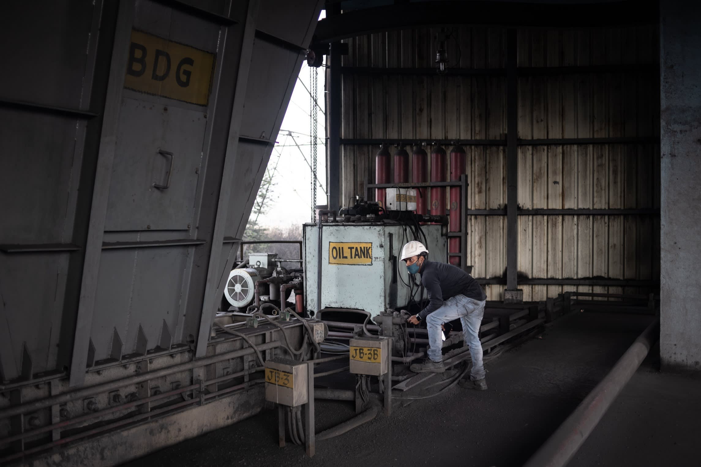 A mine worker monitors coal loaded mechanically onto a train at a silo near the Bhubaneswar mine in Angul district