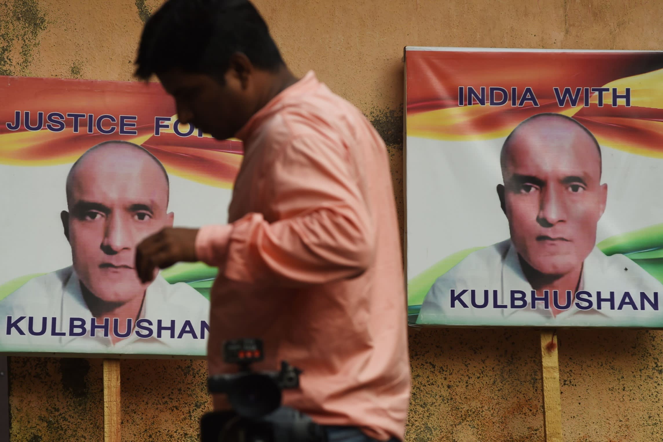 A person walks past placards with the picture of Kulbhushan Jadhav, who was arrested by Pakistani authorities in 2016 on charges of spying for India’s R&AW