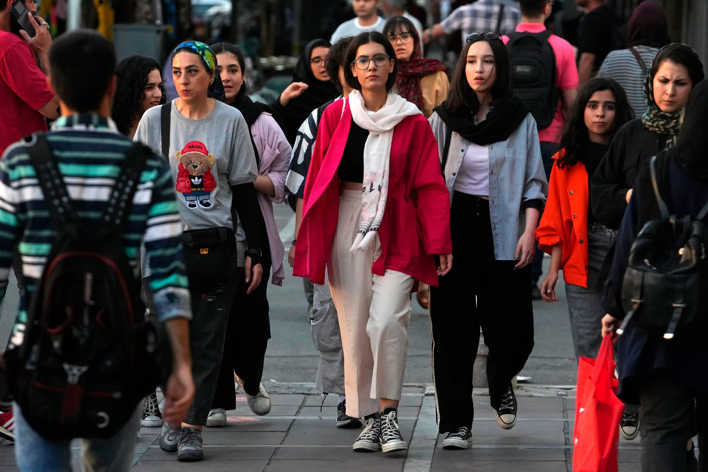Iranian women, some without wearing their mandatory Islamic headscarves, walk in downtown Tehran