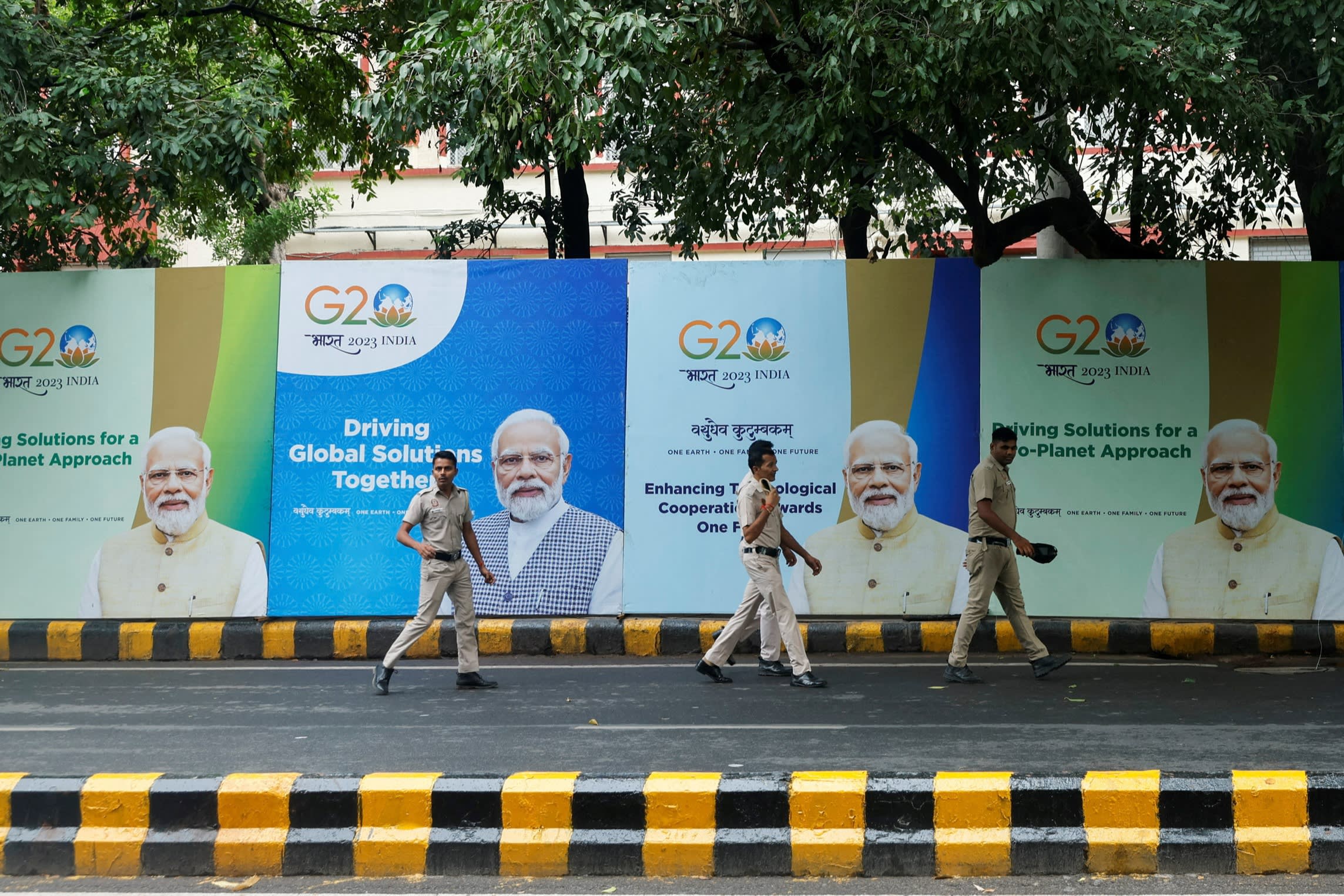 Police officers walk past posters with the picture of India’s Prime Minister Narendra Modi on the first day of the G20 summit in New Delhi on Saturday