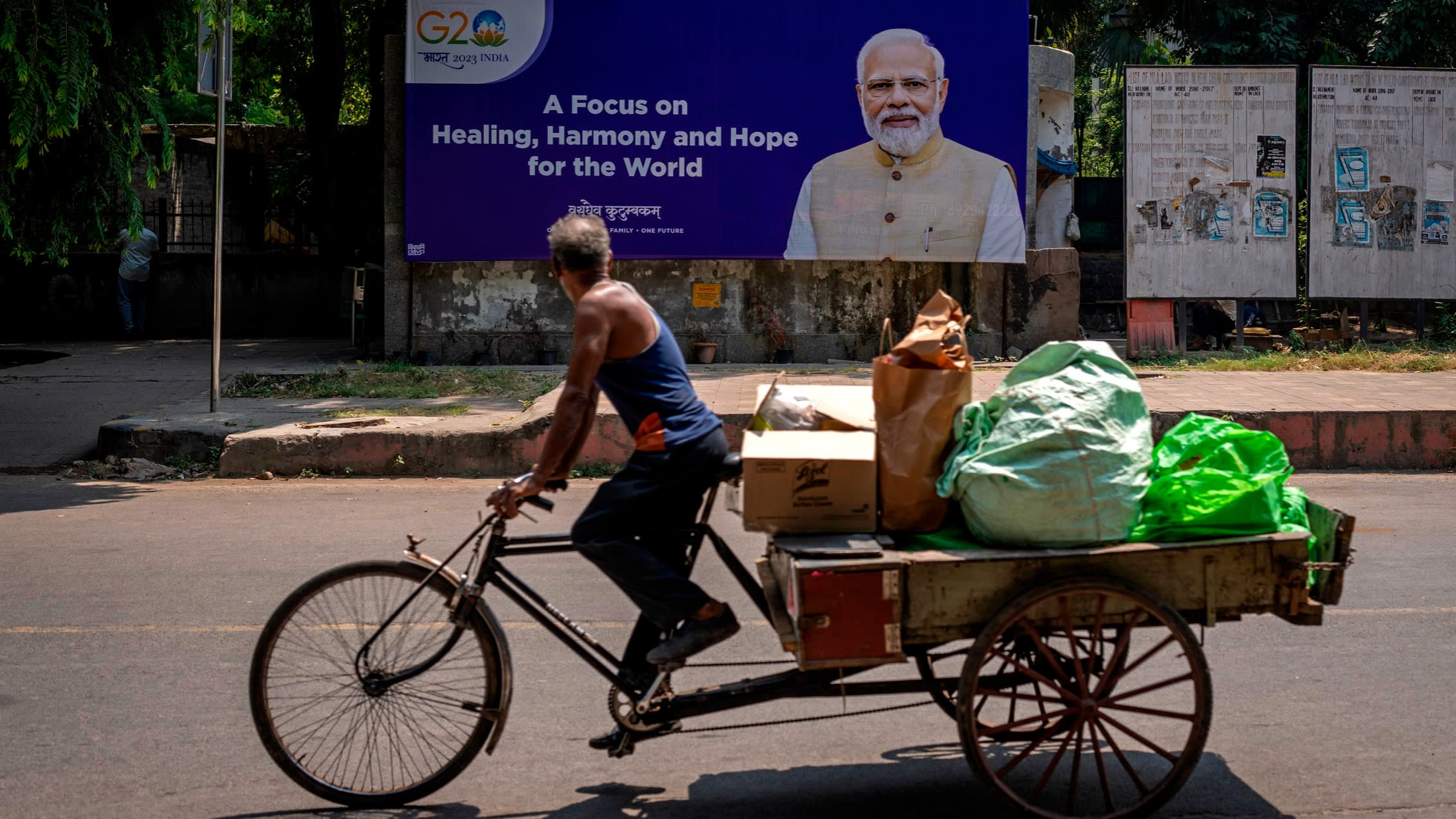 A man rides a cycle rickshaw past a billboard featuring Indian Prime Minister Narendra Modi ahead of this week’s summit of the G20 nations in New Delhi