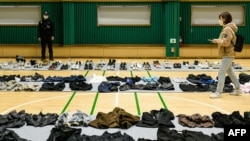 FILE - A journalist walks amongst personal belongings retrieved from the scene of a fatal Halloween crowd surge that killed more than 150 people in the Itaewon district, in Seoul, South Korea.