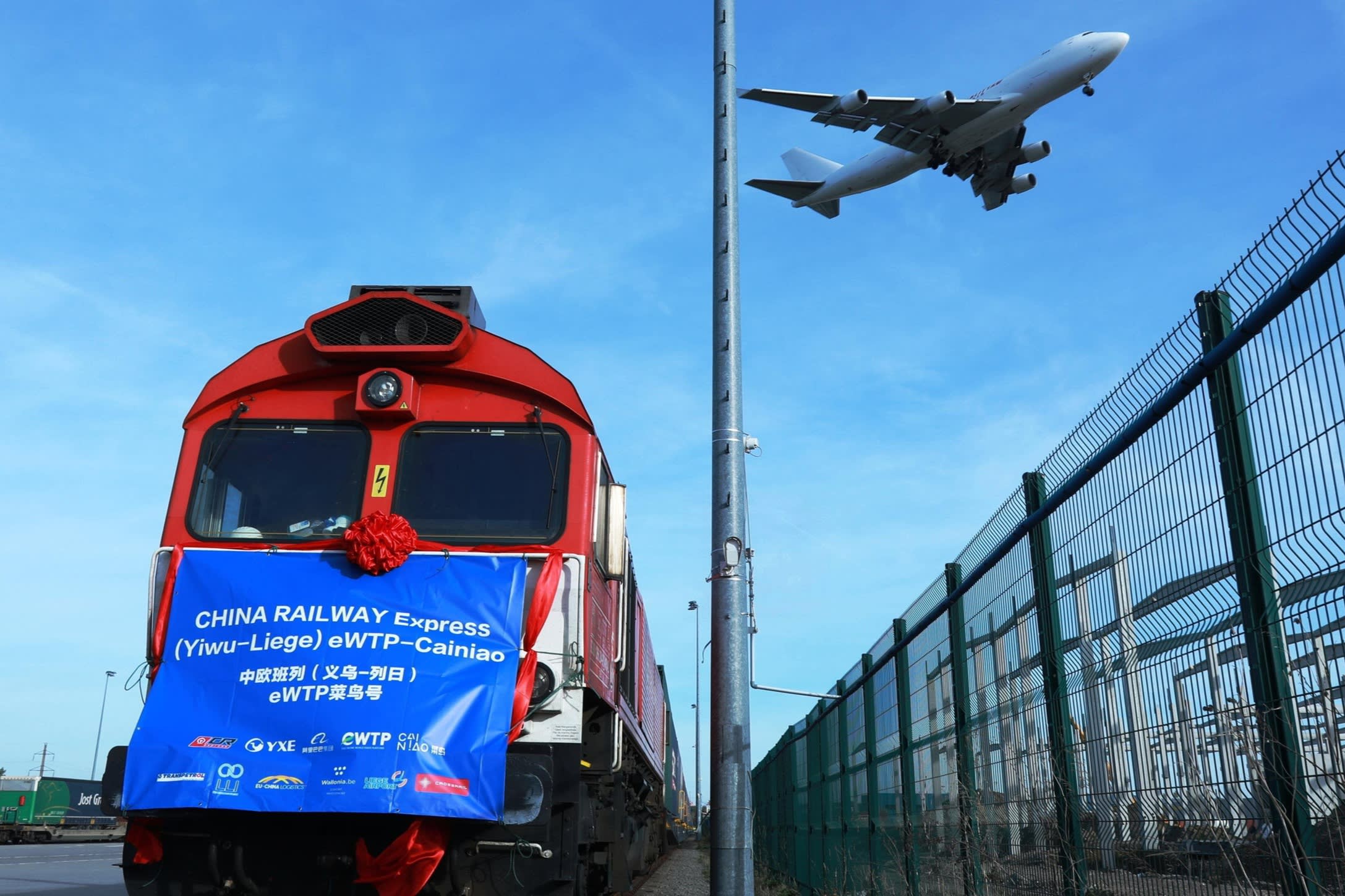 Airplane flies above a train