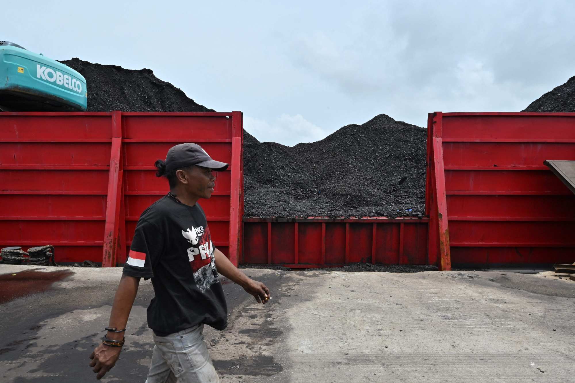 A man walks past a pile of coal at the Karya Citra Nusantara (KCN) Marunda port in Jakarta on January 17, 2022. Photo: AFP