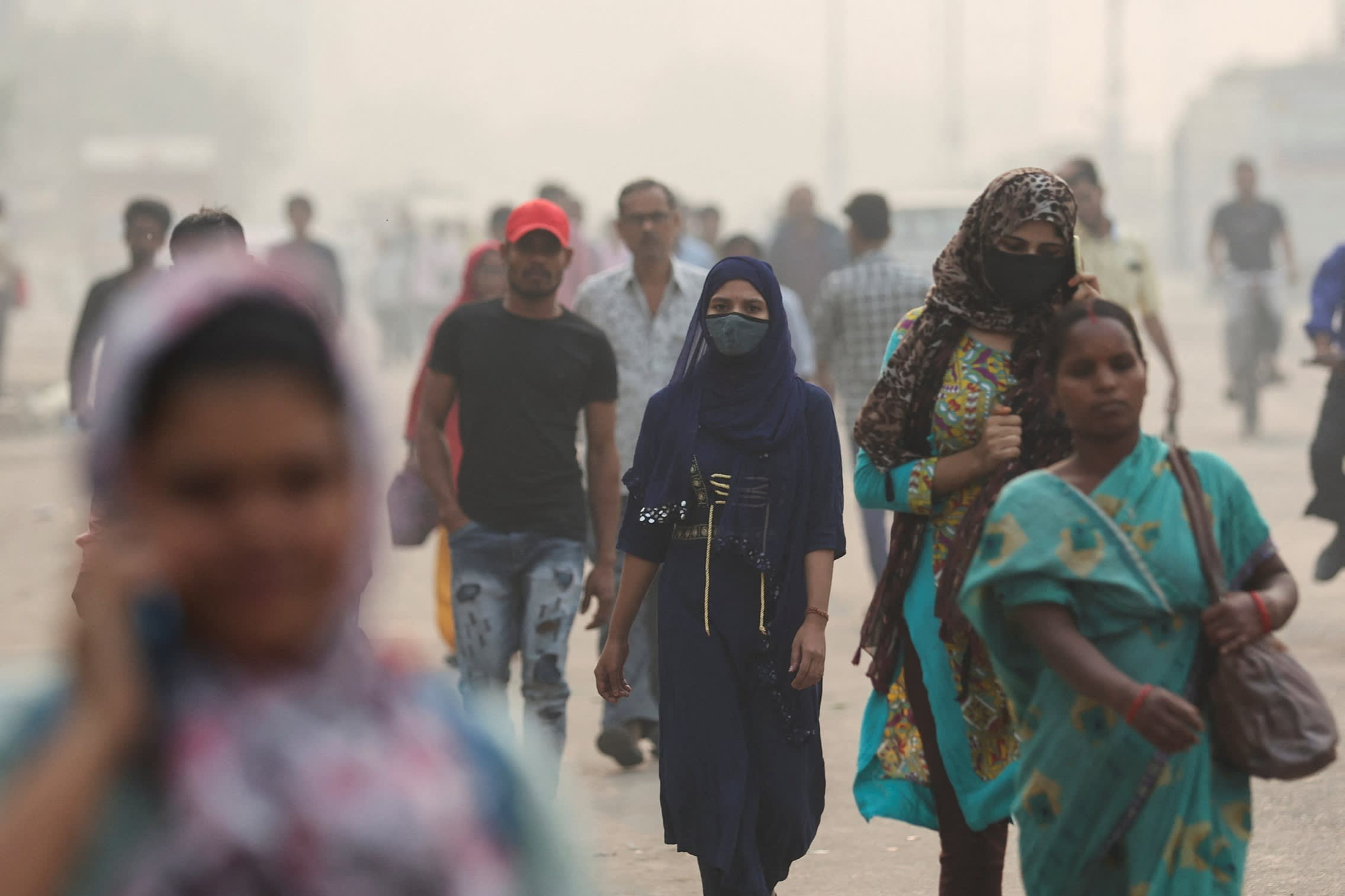 A woman in a facemask and other people walking in smog
