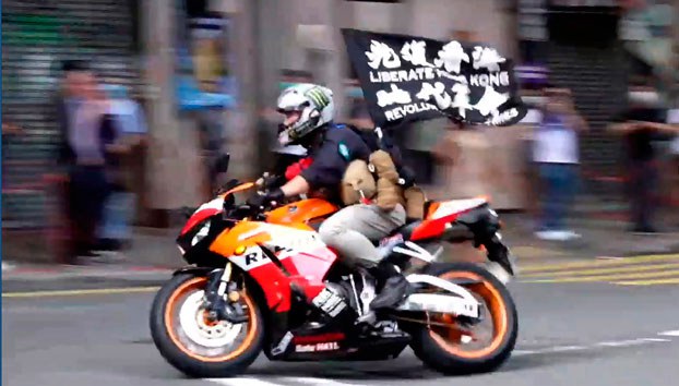 ENG_CHN_HKNatSec_11302023.2.jpg Motorcyclist Tong Ying-kit carries a flag reading 'Liberate Hong Kong, Revolution of our times' during a protest in Hong Kong on the anniversary of its return to China, July 1, 2020. (Cable TV Hong Kong via AP)