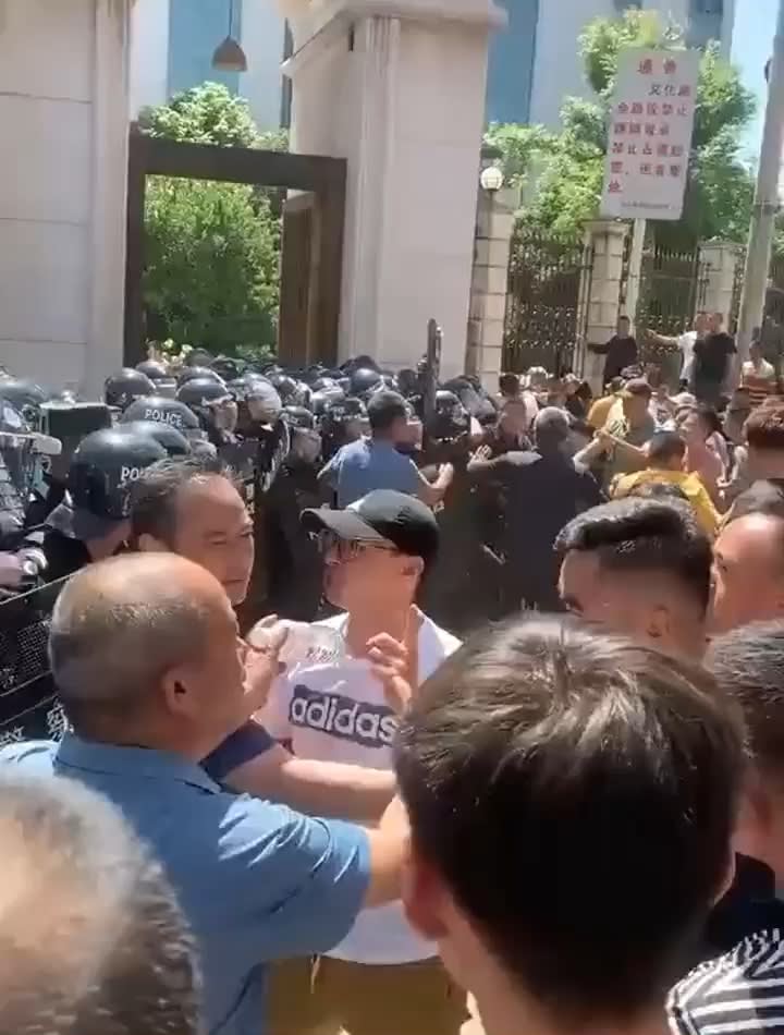 A crowd clashing with police outside of a mosque.