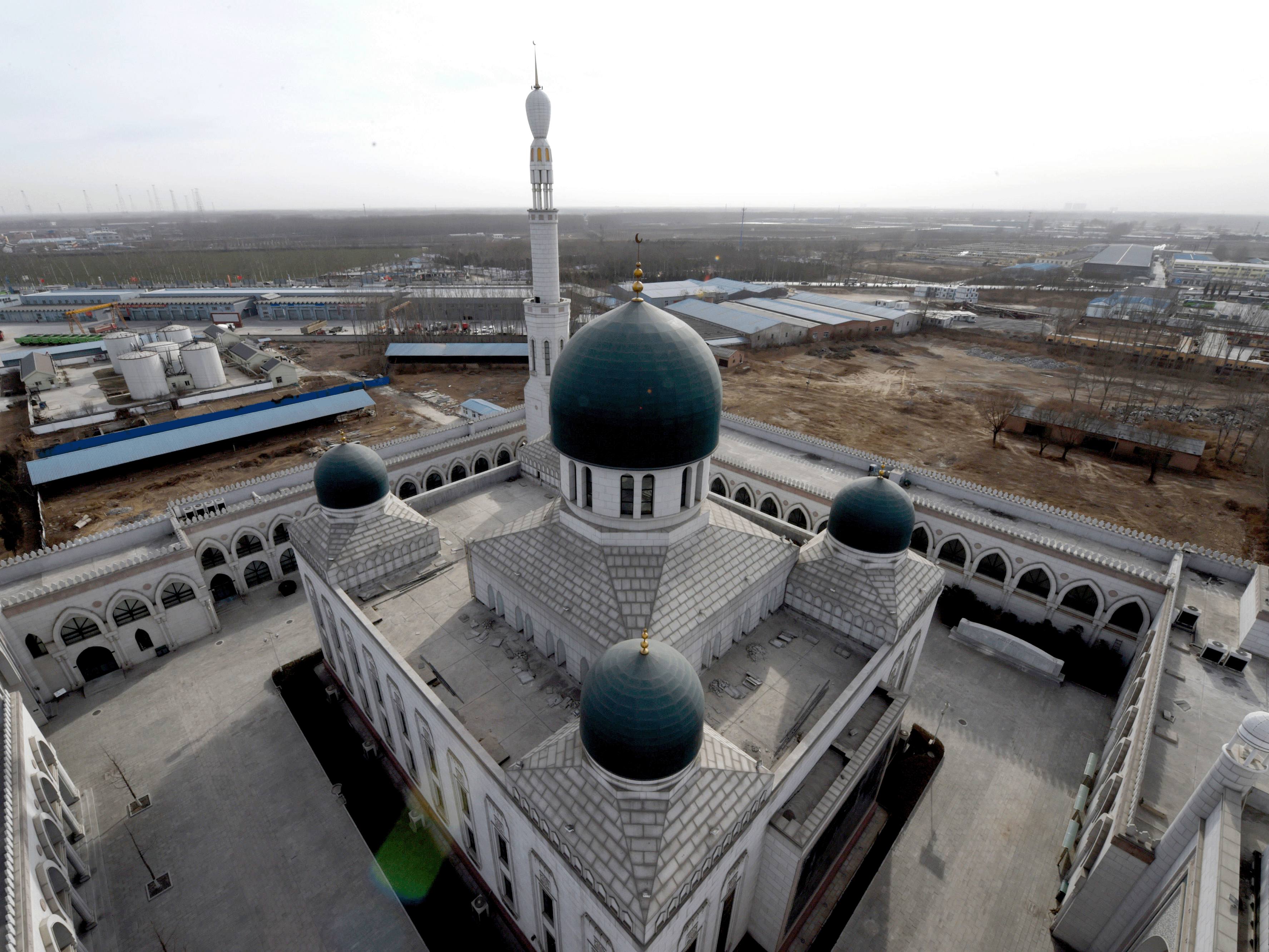 The Doudian Mosque, a large square building with a courtyard containing another square prayer hall. The entrance gate, central hall, and corners are topped with domes and minarets extend towards the sky.
