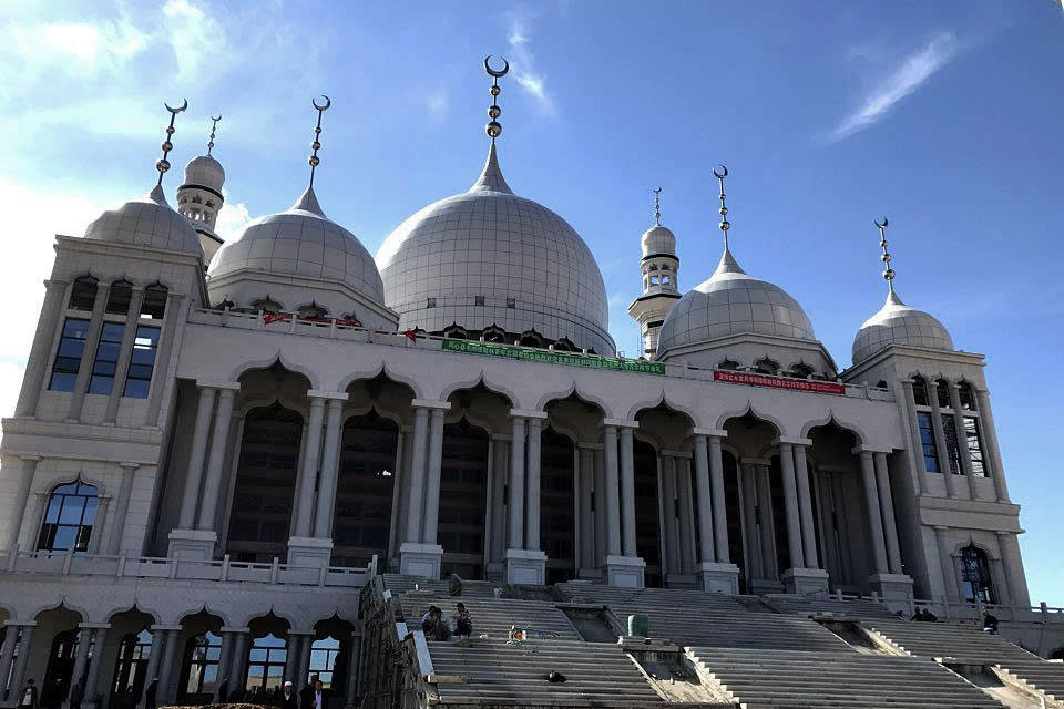 The Weizhou Grand Mosque, a large white building with a number of domes and minarets extending towards the sky.