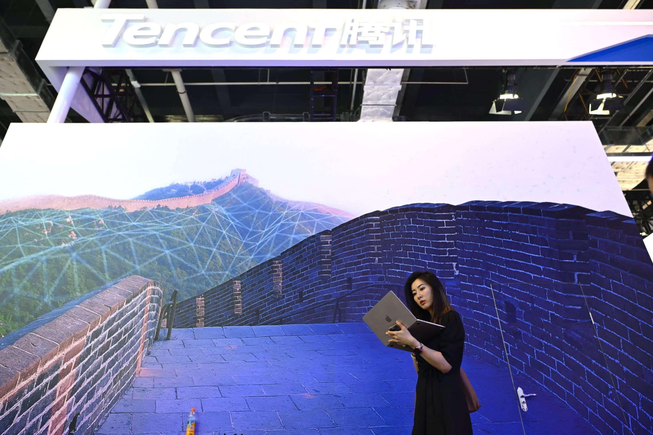 A woman looks at her laptop in front of Tencent’s booth during the World Artificial Intelligence Conference