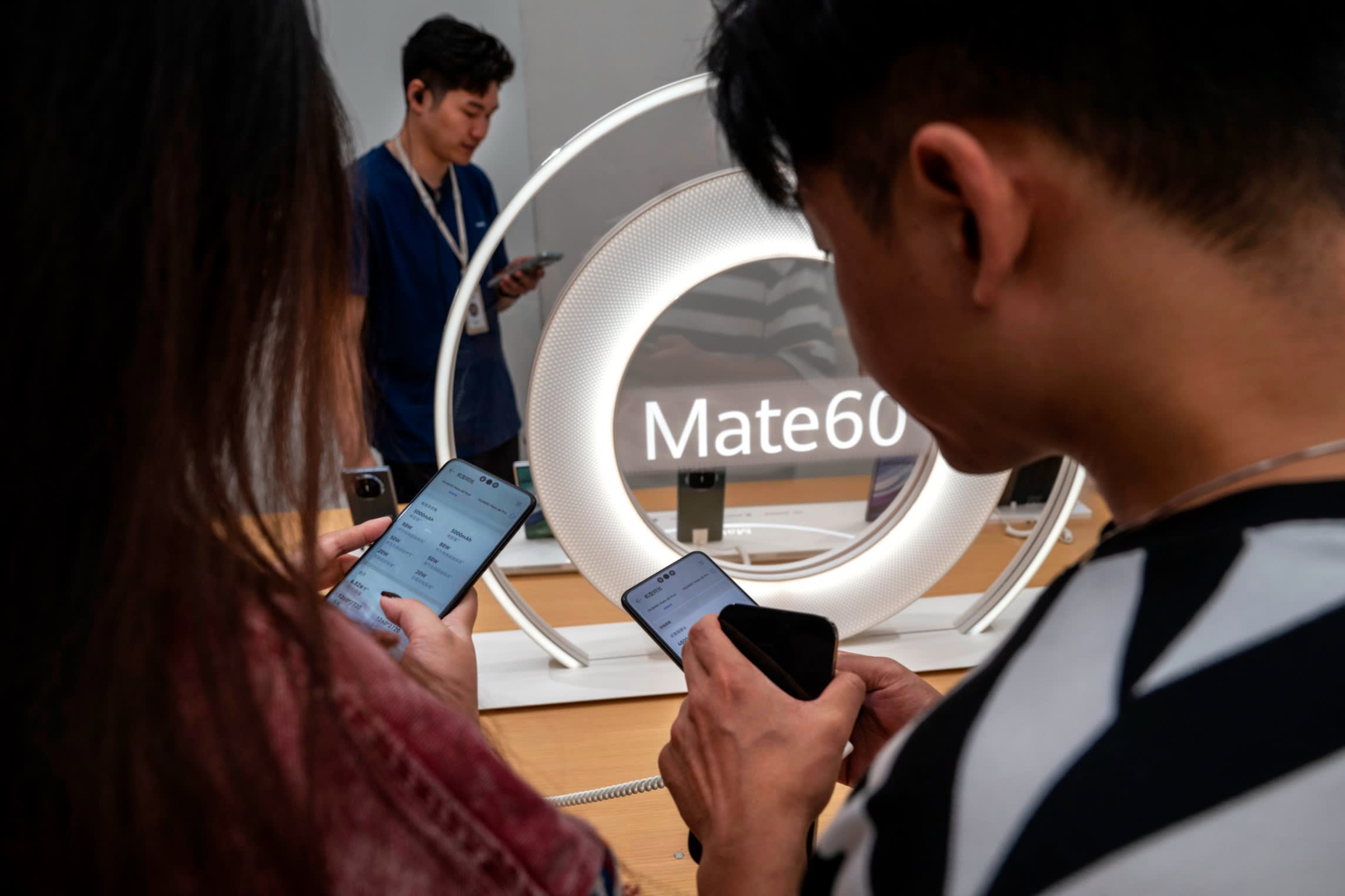 View of two people’s shoulders as they look at Mate 60 smartphones