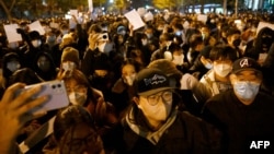 Protesters march along a street during a rally for the victims of a deadly fire as well as a protest against China's harsh Covid-19 restrictions in Beijing on Nov. 28, 2022.