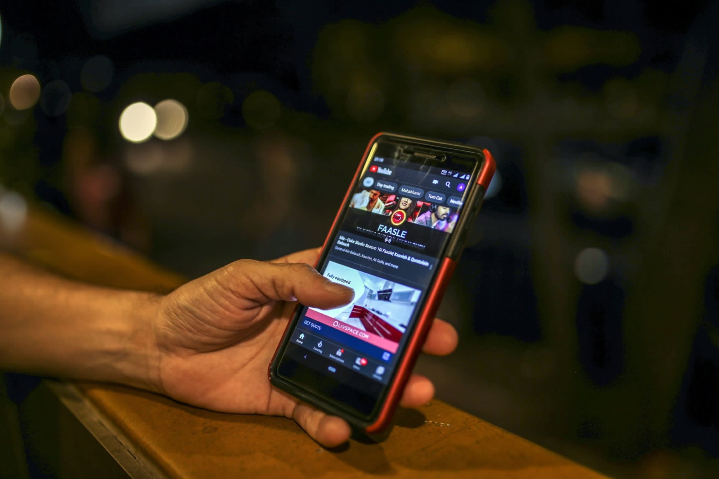 A hand holding a mobile phone with video content on the screen