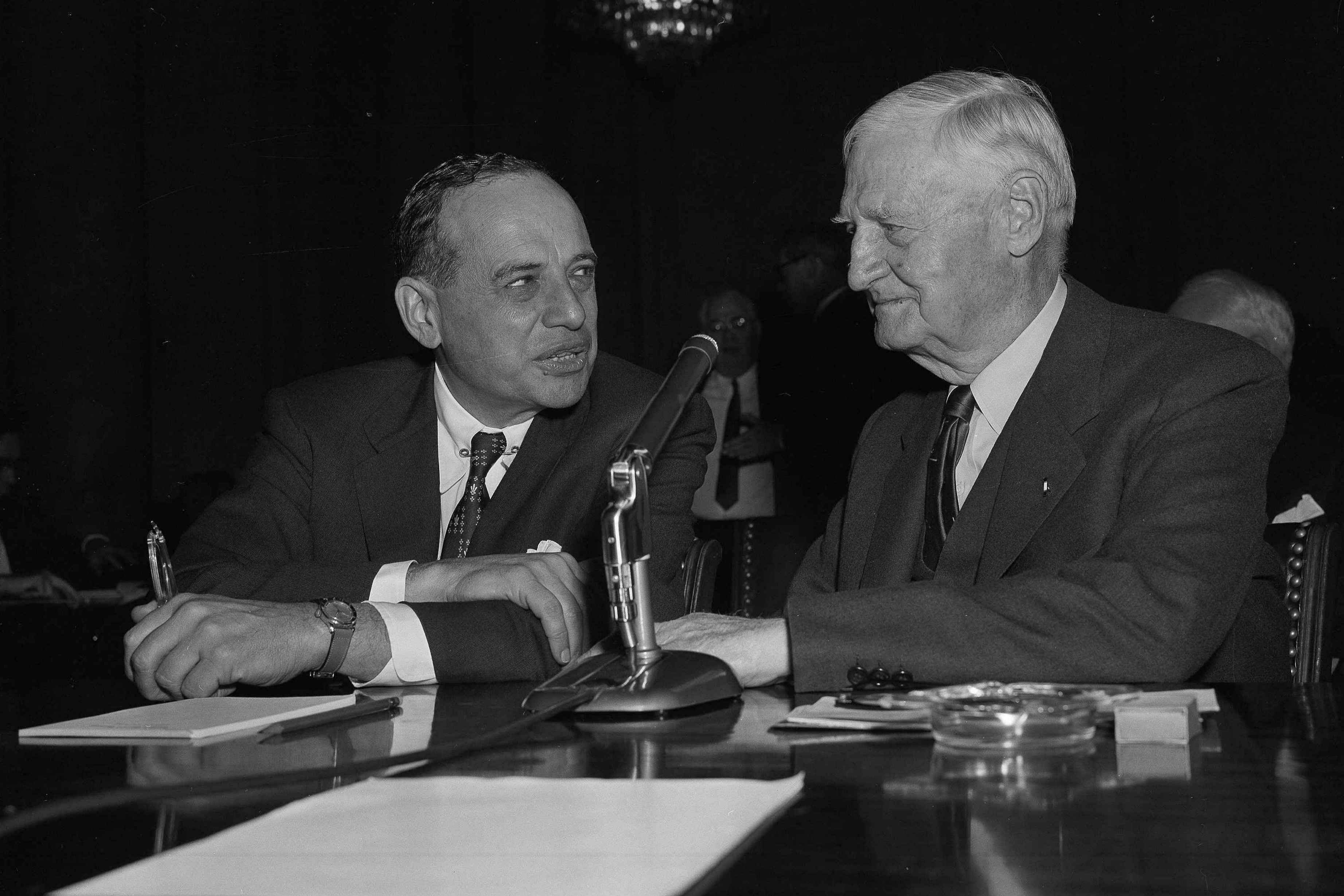 Benjamin Graham speaking with another man, in a black and white photo from the 1950s
