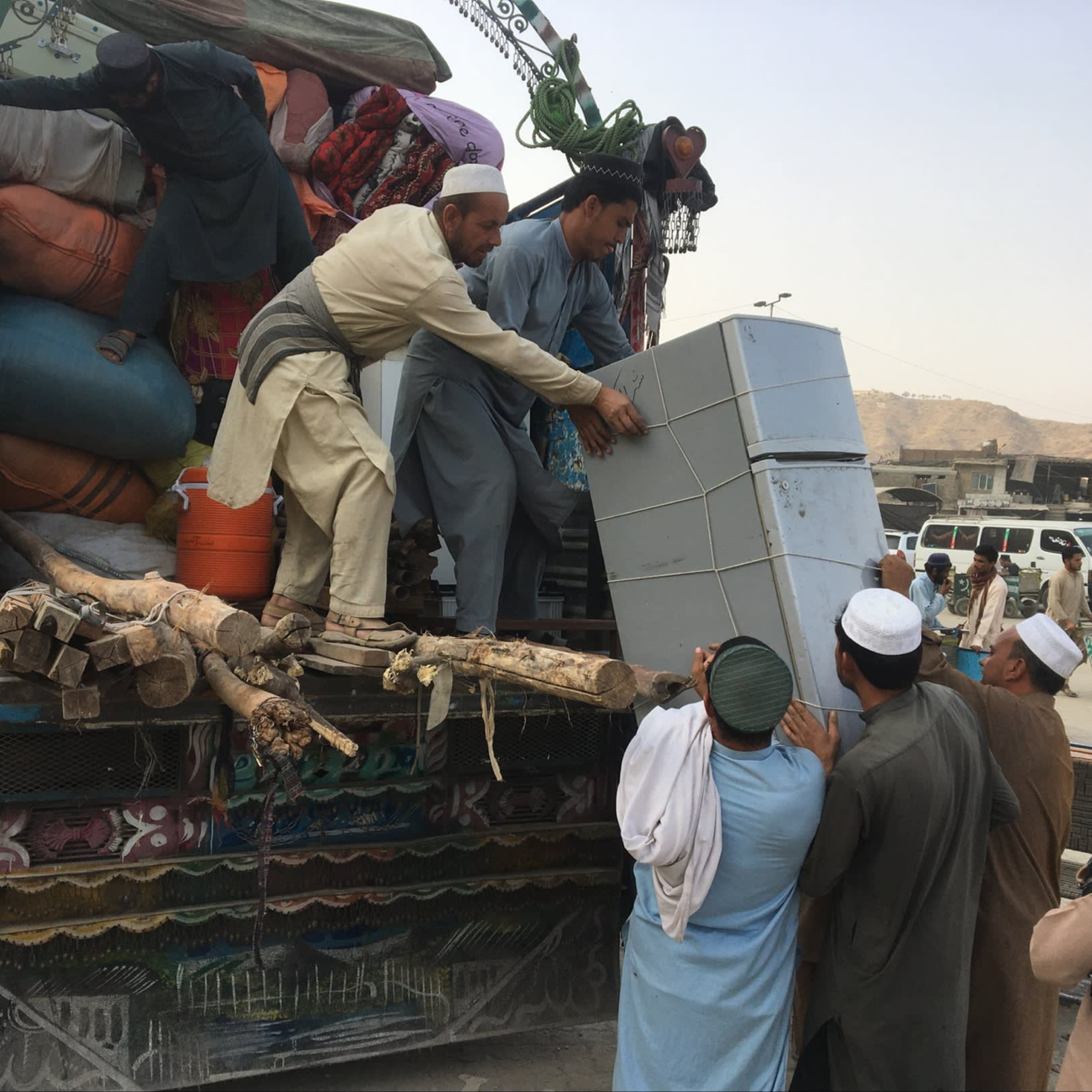 Men pushing a fridge on to a truck