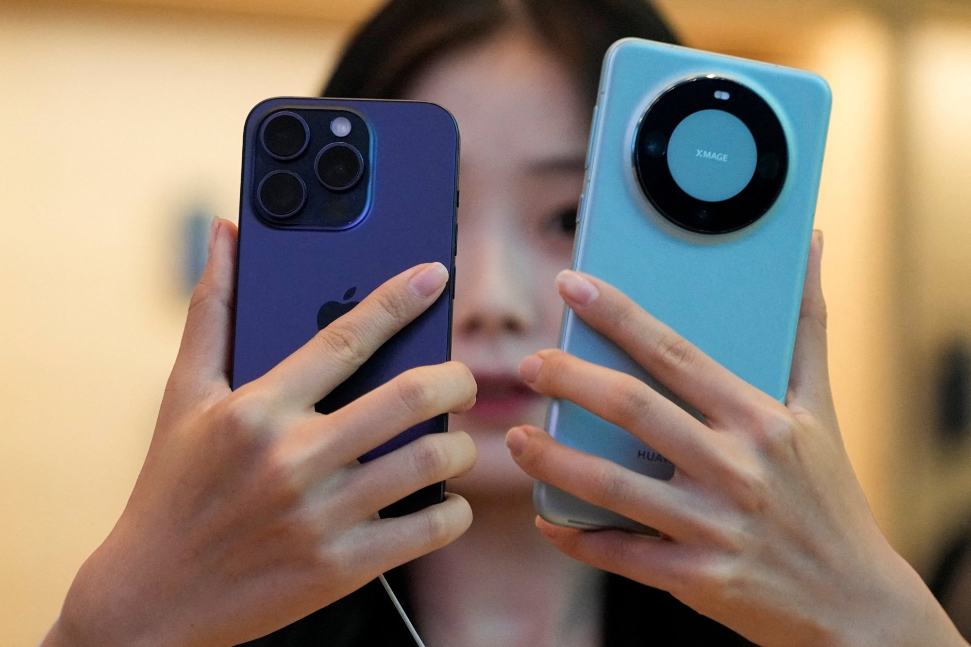 A woman looks at a new iPhone 15 Pro and a Huawei Mate 60 Pro at an Apple store in Shanghai on September 22, 2023. Photo: Reuters