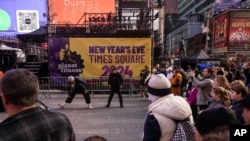 Tourists walk around New Year's Eve sign in Times Square, Dec. 29, 2023, in New York.
